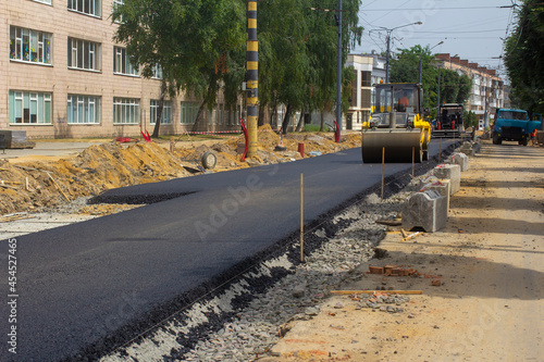 An asphalt paver and a roller are in operation.