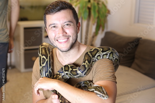 Man with large Burmese python at home 