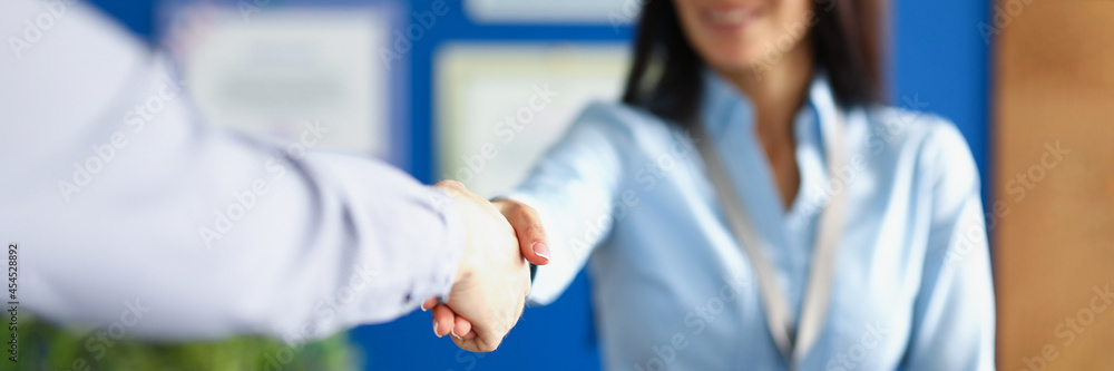 Closeup of handshake of businesswoman with badge and client