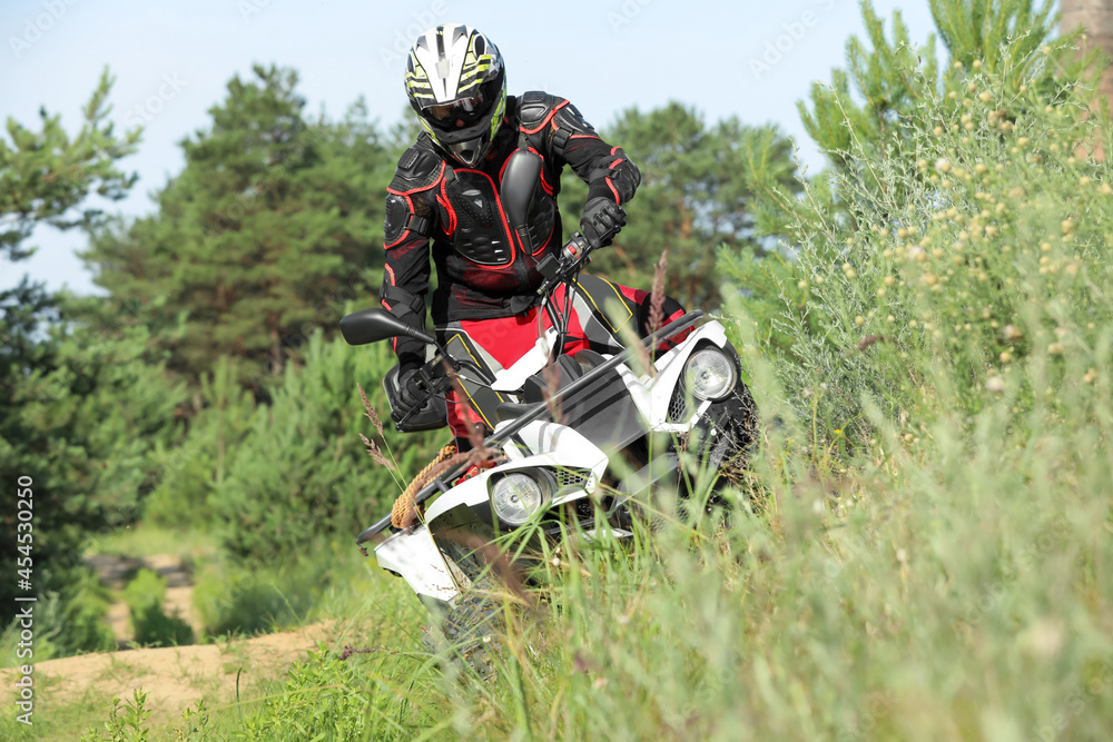 Man driving modern quad bike on sandy road near forest. Extreme sport Man driving modern quad bike on sandy road near forest. Extreme sport