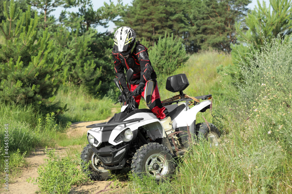 Man driving modern quad bike on sandy road near forest. Extreme sport Man driving modern quad bike on sandy road near forest. Extreme sport