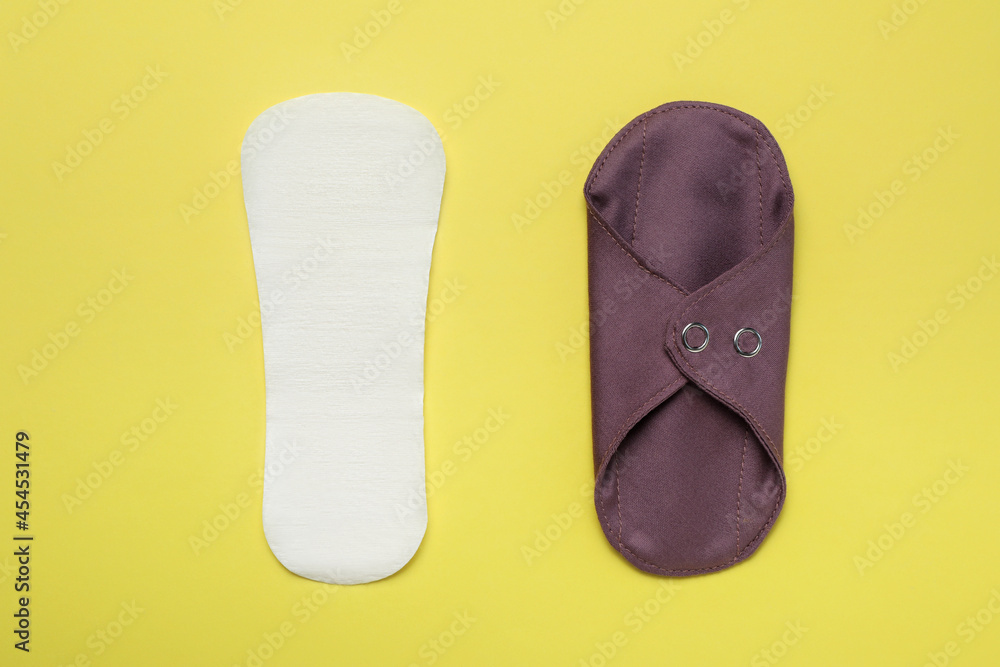 Pantyliner and reusable cloth menstrual pad on yellow background, flat lay Pantyliner and reusable cloth menstrual pad on yellow background, flat lay