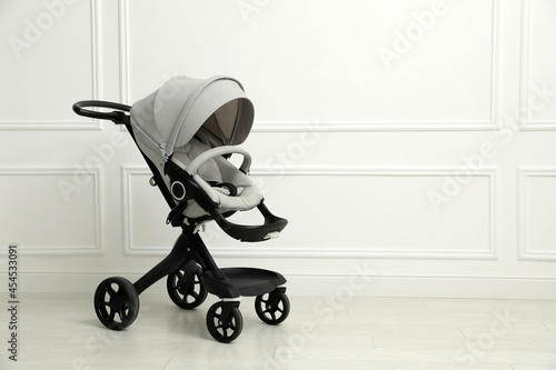 Bild auf Leinwand Baby carriage. Modern pram near white wall, space for text