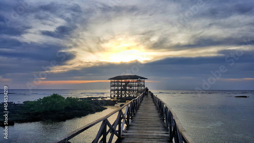 Slika na platnu Long wooden pier with an alcove under a cloudy dark sunset sky