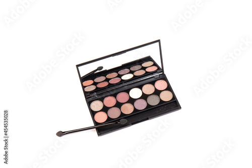 Eyeshadow palette. Black plastic case with twelve powder matte, glitter paint sample in purple, pink, brown, vanilla colors and brush. Top view makeup box isolated on white background