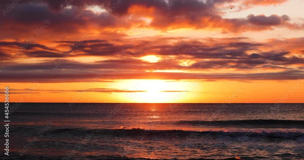 Ocean beach sunrise with dramatic sky clouds and golden sun rays over the waves Ocean beach sunrise with dramatic sky clouds and golden sun rays over the waves