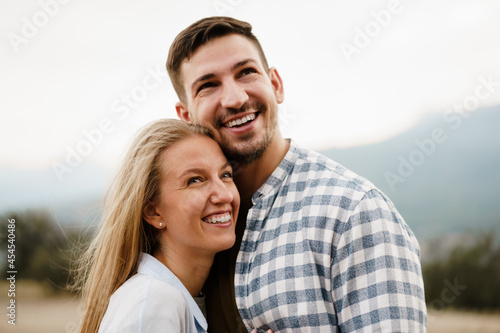 Happy loving couple hiking and hugging in mountains