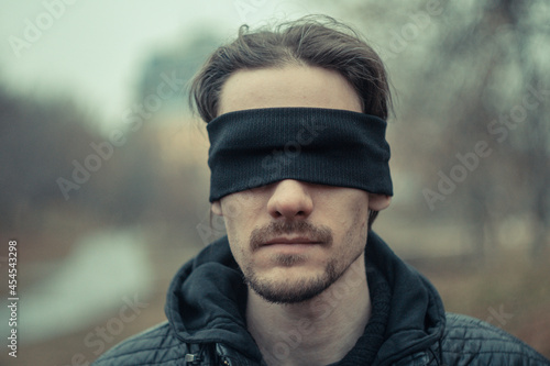 a man with a black blindfold over his eyes photo