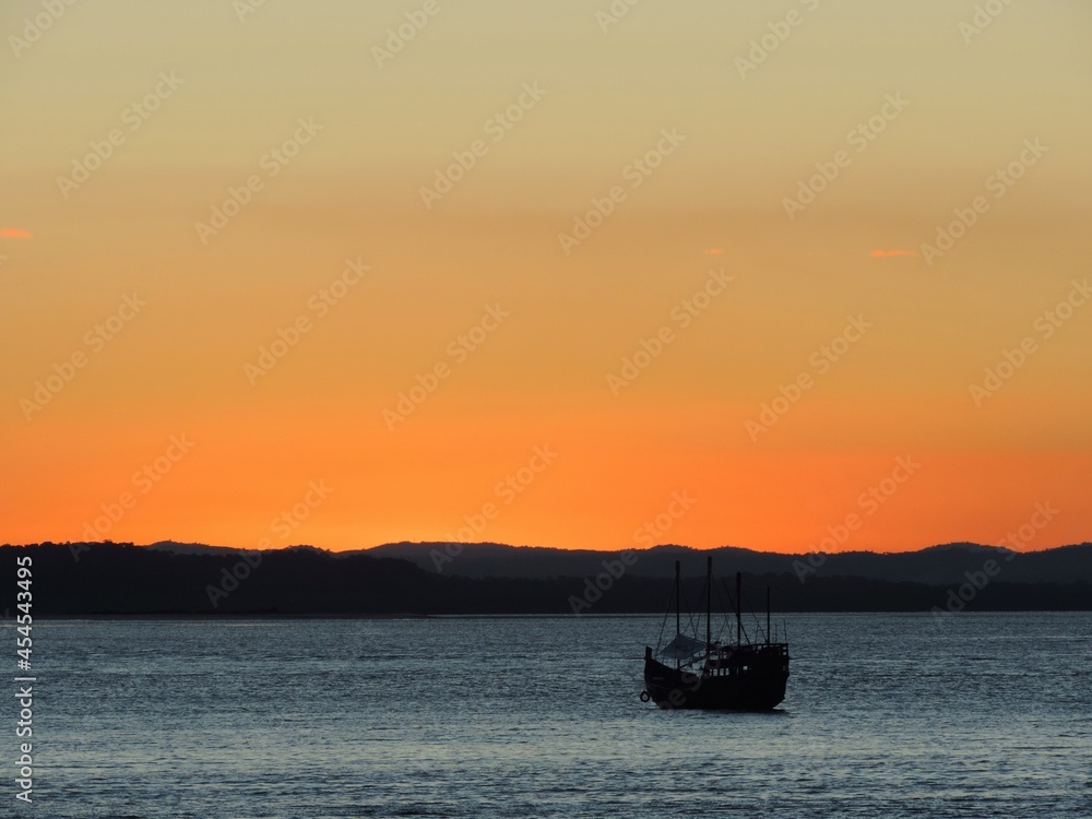 Sunset over the river with caravel boat silhouette and an orange sky during the golden hour