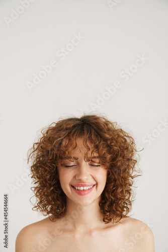Half-naked ginger woman smiling while posing with her eyes closed