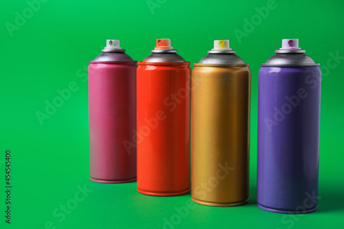 Cans of different graffiti spray paints on green background