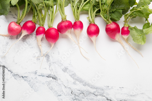 Red radish with green tops on a light background
