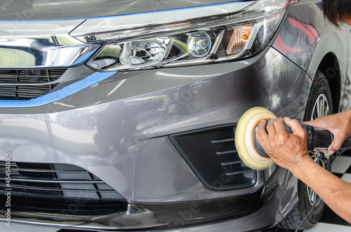 Car detailing - Male mechanic holding car polishing machine. Auto industry, car polishing and painting and repair shop. © khunkornStudio