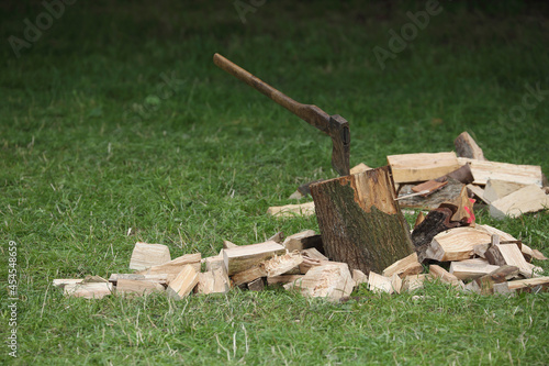 An ax in a chopping block and a pile of firewood