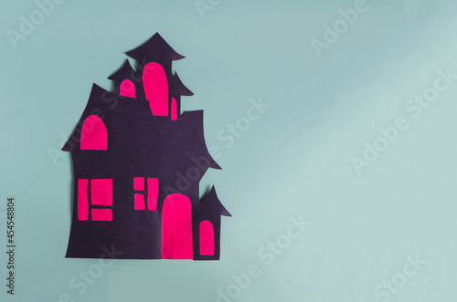 An application made of cardboard is a dark house with red windows on a light background. Children's creativity for the Halloween holiday