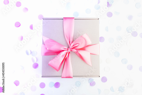 present gift box with pink bow with festive confetti. Birthday, weeding, Christmas holiday and congratulation concept. Flat lay style. © artemidovna