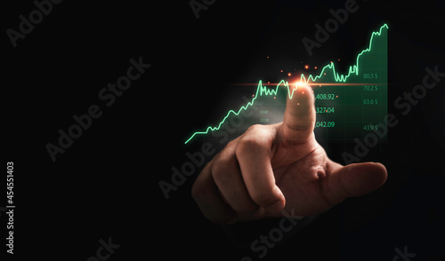 Trader hand touching to stock market graph chart on dark background for technical investment analysis concept.