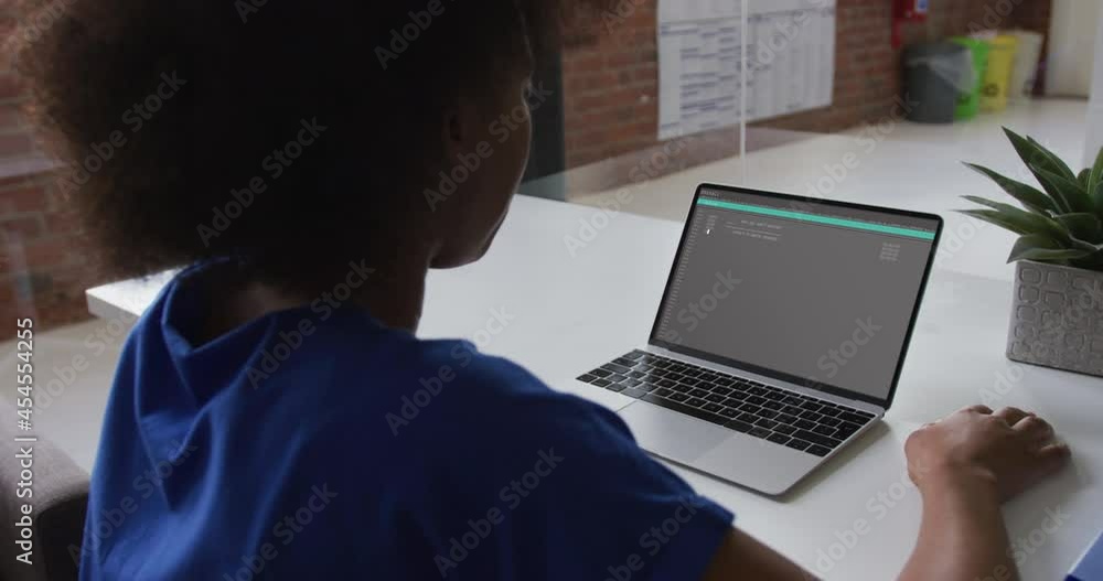 African american woman sitting at desk watching coding data processing on laptop screen African american woman sitting at desk watching coding data processing on laptop screen