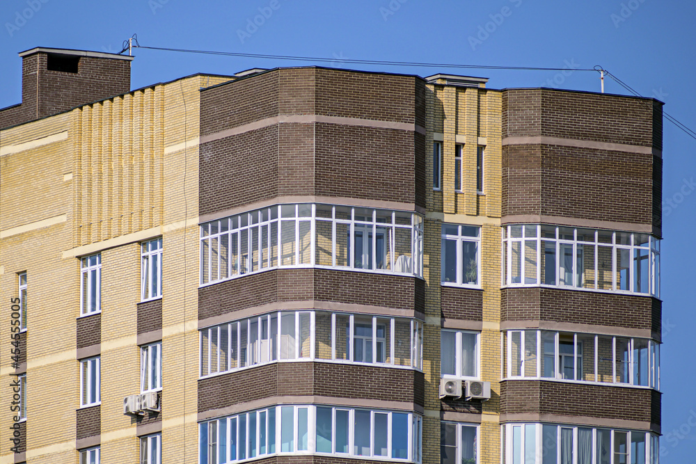The upper part of an apartment building on a blue sky background