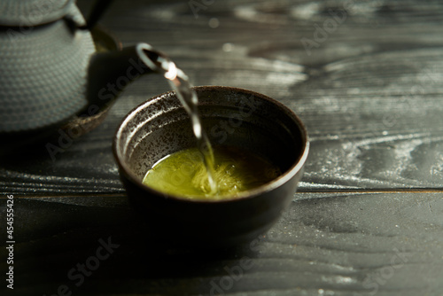Japanese organic matcha green tea in cup on black wood background. Healthy product from the nature typical of the oriental tradition. Japanese tea ceremony.