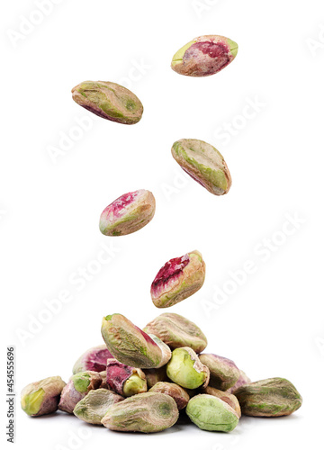 Peeled pistachios fall on a pile on a white background. Isolated