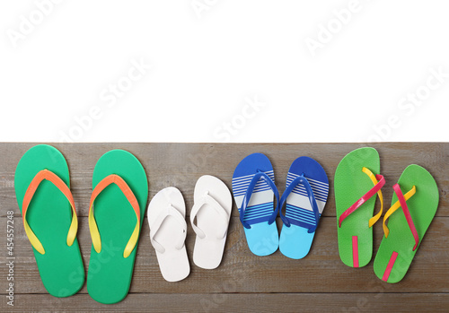 Different stylish flip flops on wooden table against white background, top view