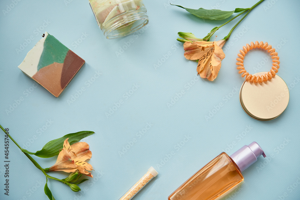Beauty cosmetic products top view: natural oil, eye patches, natural soap on blue background with alstroemeria flowers decorations. Teal and orange.Copy space Beauty cosmetic products top view: natural oil, eye patches, natural soap on blue background with alstroemeria flowers decorations. Teal and orange.Copy space