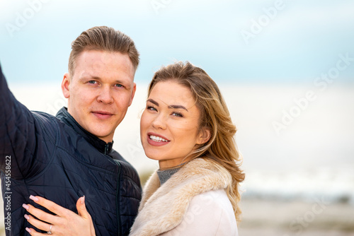Beautiful young happy woman hugging cuddle young boyfriend while taking selfie photo on sunny beach.Close up.