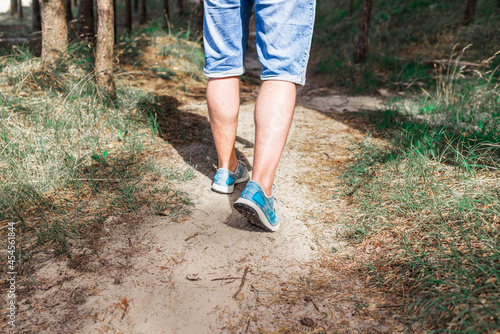 Man walking or running on path in forest summer natureo outdoors, sport shoes and exercising on fotpath.Close-up.