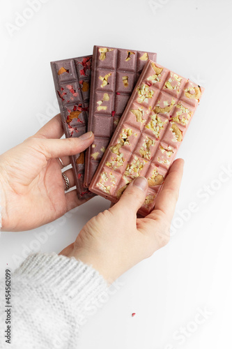 Hands holding chokolate bar of handmade glutenfree chokolate with nuts and berries on white background photo