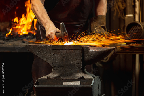 Canvas Print Close-up working powerful hands of male blacksmith forge an iron product in a blacksmith