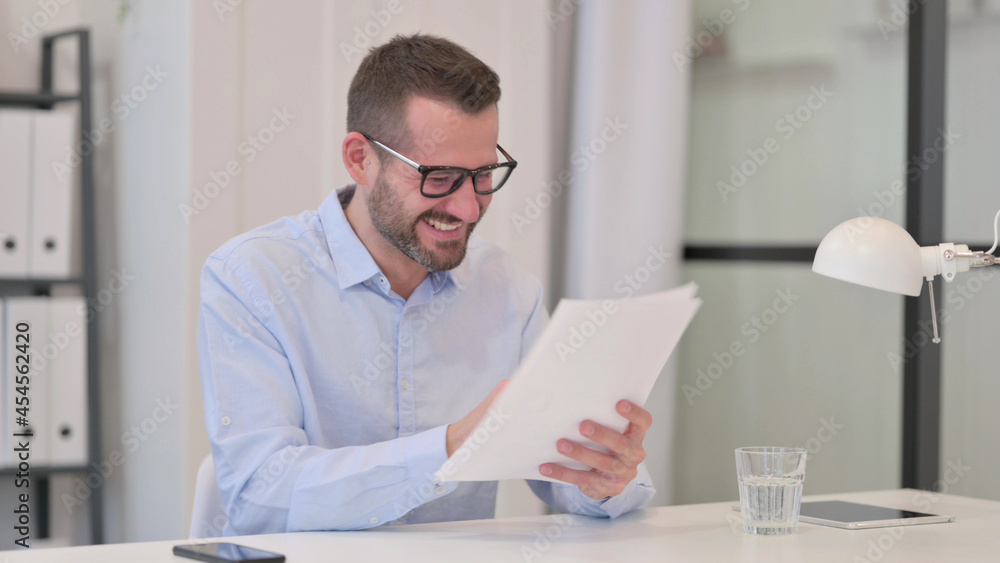 Middle Aged Man Excited by Success on Documents 