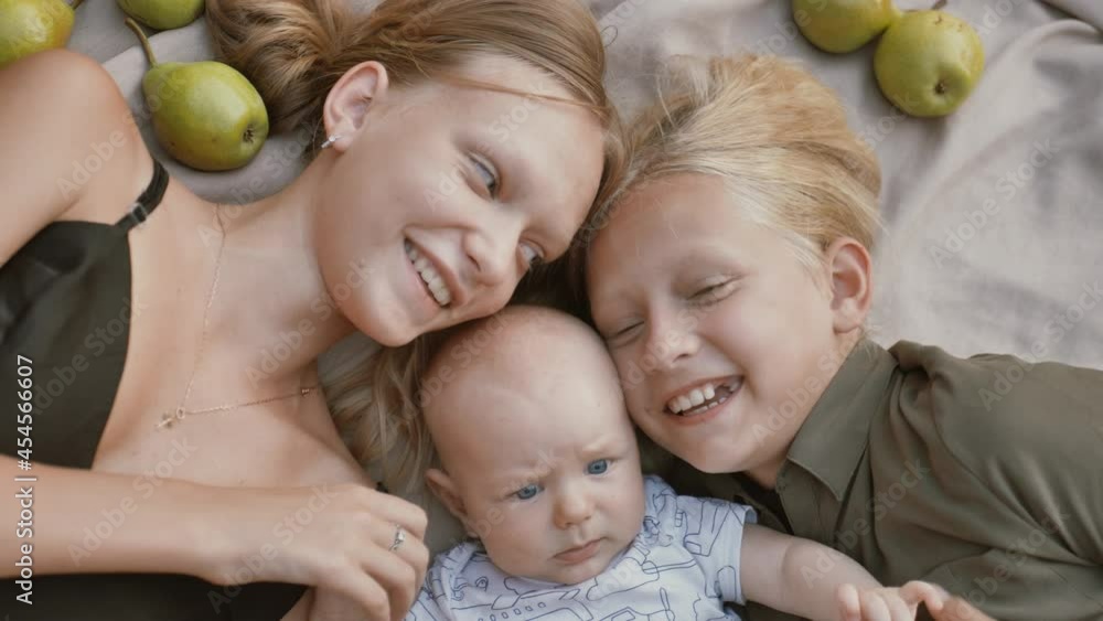 Selfie of friends, two sisters and a little brother lying on the bed and taking a selfie in front of the camera. Family taking selfie with smartphone. Close up Selfie of friends, two sisters and a little brother lying on the bed and taking a selfie in front of the camera. Family taking selfie with smartphone. Close up