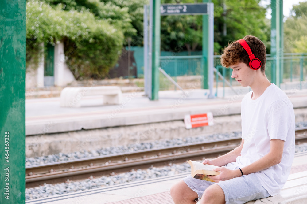 Teen boy reading a red book with red headphones. Teen boy reading a red book with red headphones.
