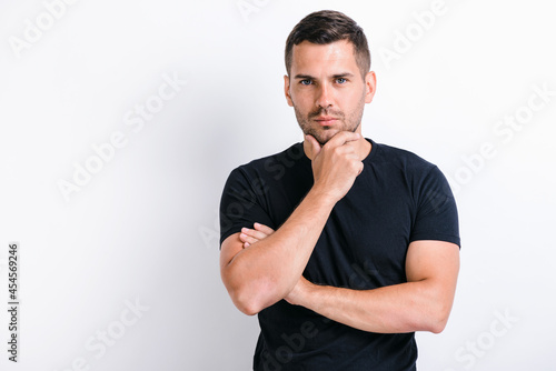 Hmm, let's think! Portrait of pensive handsome man in worker touching chin while pondering plan, having doubts about difficult choice, not sure. Studio shot isolated on white background