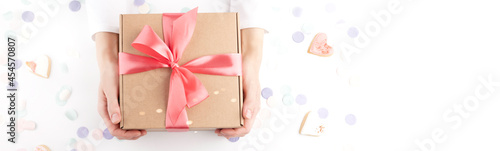 Obraz na płótnie woman hands holding gift box with pink bow, confetti, small hearts w salonie