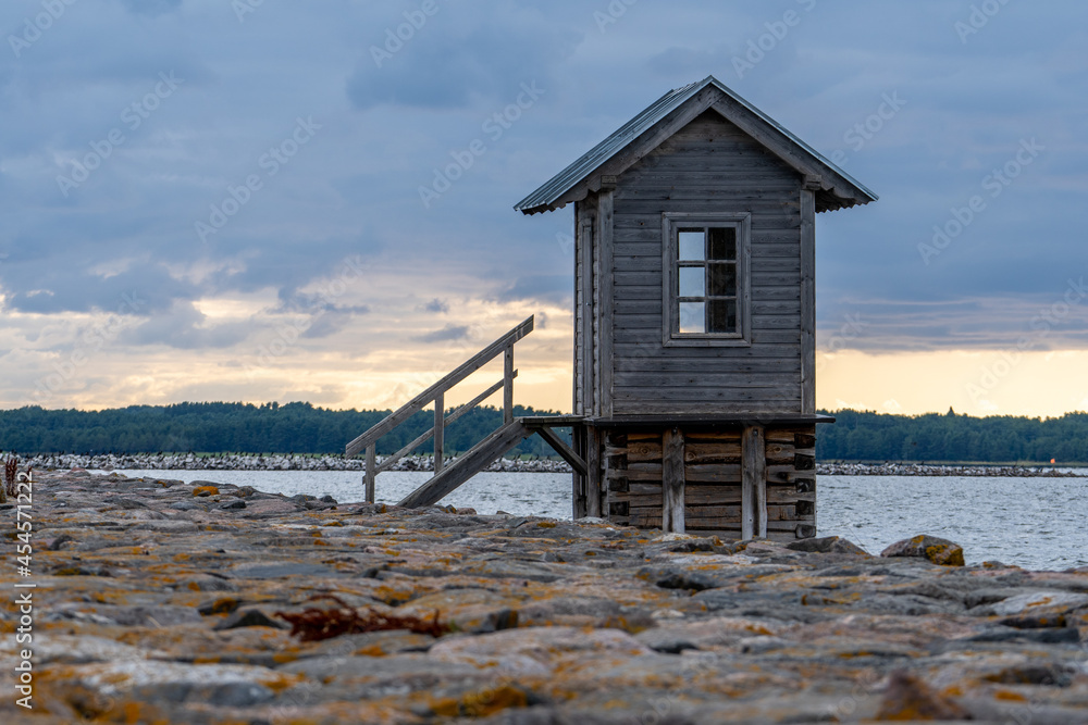 Estonia, on the island of Hiiumaa, next to a rocky pier, there is a small wooden house rising above the water