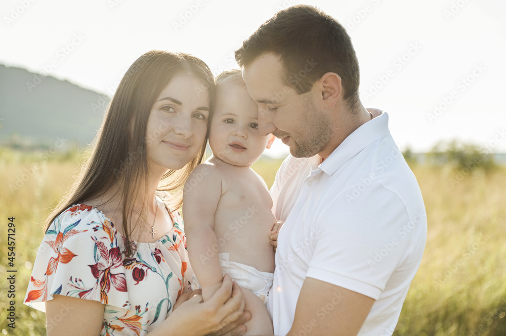 Portrait of young happy family holding in hands cute toddler son at summer day on field Portrait of young happy family holding in hands cute toddler son at summer day on field