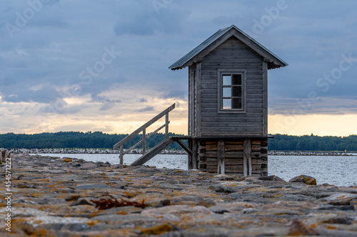 Estonia, on the island of Hiiumaa, next to a rocky pier, there is a small wooden house rising above the water photo