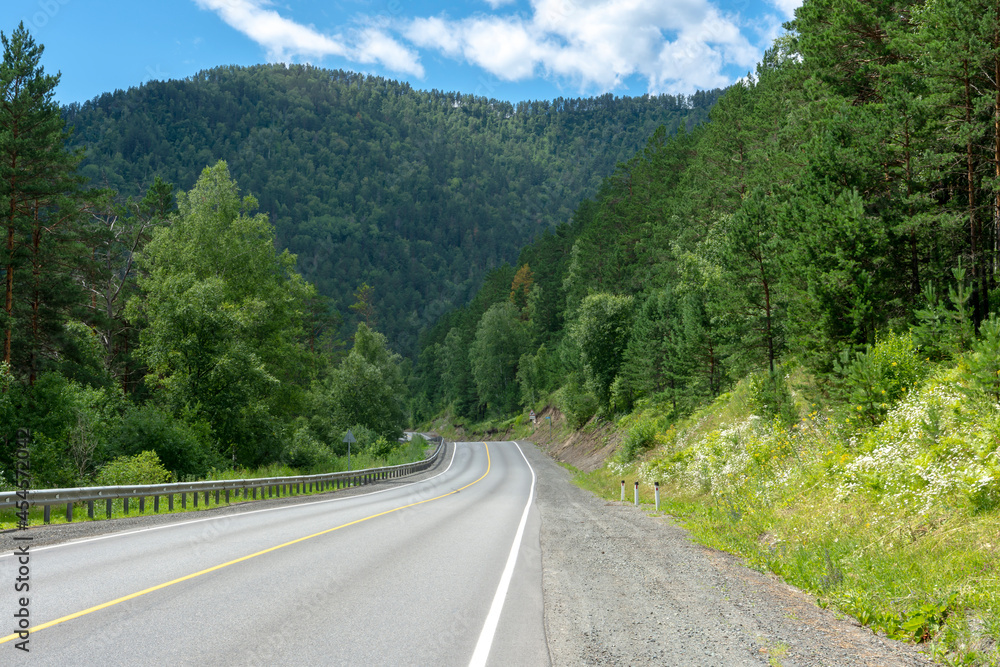 highway road and mountain peaks on the background of a blue sky with clouds highway road and mountain peaks on the background of a blue sky with clouds