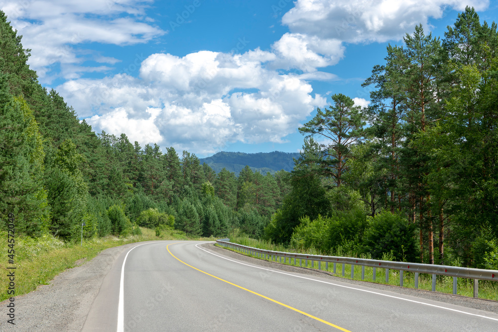 highway road and mountain peaks on the background of a blue sky with clouds highway road and mountain peaks on the background of a blue sky with clouds