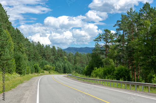 highway road and mountain peaks on the background of a blue sky with clouds