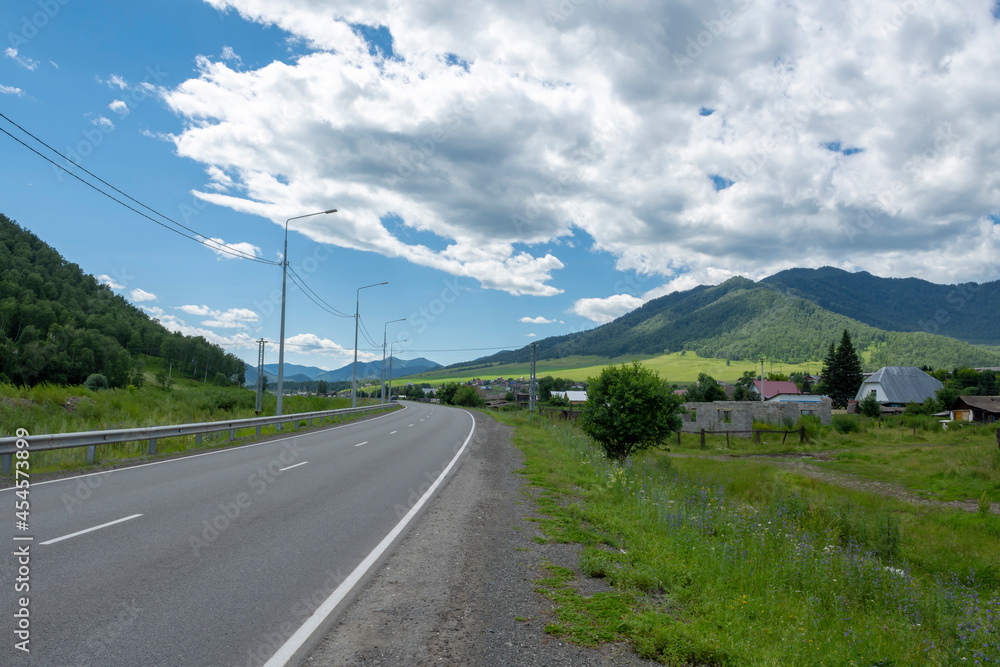 highway road and mountain peaks on the background of a blue sky with clouds highway road and mountain peaks on the background of a blue sky with clouds