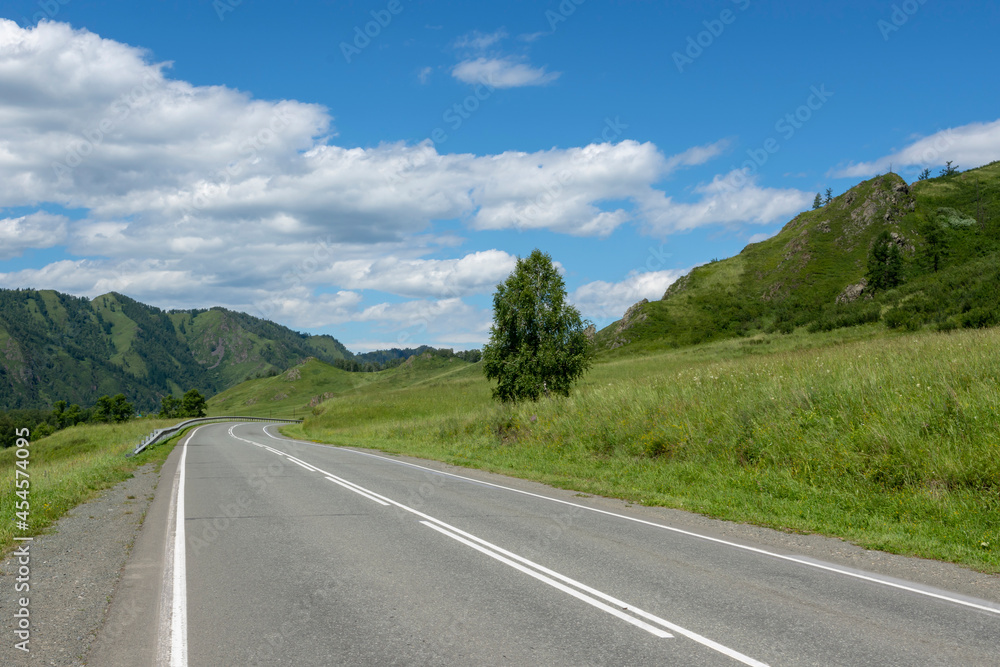 Fototapeta premium highway road and mountain peaks on the background of a blue sky with clouds