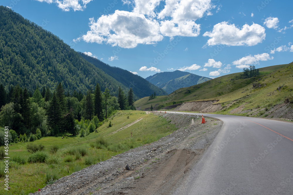 mountain peaks on the background of a blue sky with clouds and a highway