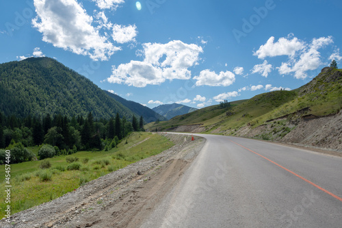mountain peaks on the background of a blue sky with clouds and a highway