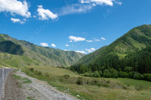 mountain peaks on the background of a blue sky with clouds and a highway