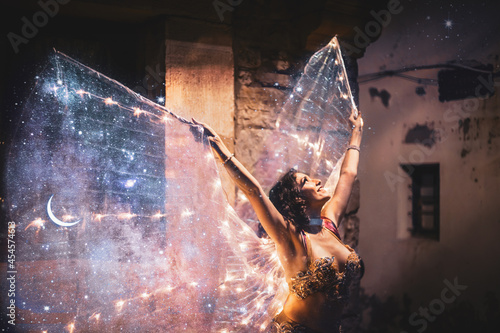 Billede på lærred Young belly dancer with galaxy wings in a castle