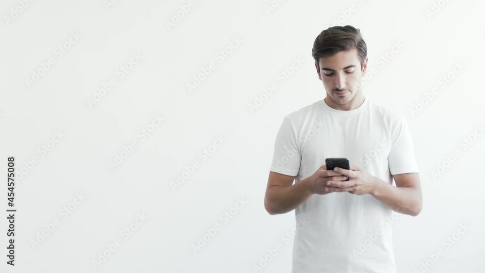 Young Caucasian Male Using Mobile Phone with Both Hands Placed on the Left with White Background Young Caucasian Male Using Mobile Phone with Both Hands Placed on the Left with White Background