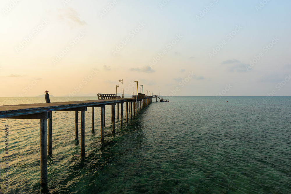 Long wooden bridge go to the sea in beautiful tropical island at sunset.